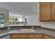 Kitchen sink with wooden cabinets and quartz countertop, large window, and a view to the living spaces at 2515 Centennial Falcon Dr, Valrico, FL 33596