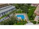 Aerial view showcases a sparkling community pool with lounge chairs, lush landscaping, and parking at 2700 Bayshore Blvd # 547, Dunedin, FL 34698