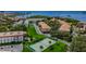 An aerial view showcases waterfront condos, manicured lawns, mature trees, parking, and a tennis court at 2700 Bayshore Blvd # 547, Dunedin, FL 34698