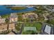 Aerial view featuring waterfront condos, parking, lush trees, and a tennis court at 2700 Bayshore Blvd # 547, Dunedin, FL 34698
