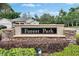 Stone entrance sign for Forest Park neighborhood with lush landscaping and a glimpse of a home at 3004 Spring Hammock Dr, Plant City, FL 33566