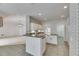 Open kitchen with island, white cabinets, and tile flooring, leading to a living area at 3004 Spring Hammock Dr, Plant City, FL 33566
