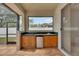 Covered outdoor kitchen featuring wood cabinets, sink, mini fridge and backyard views at 3004 Spring Hammock Dr, Plant City, FL 33566