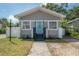 Charming bungalow featuring a bright blue front door, fresh landscaping, and updated siding at 302 W Hilda St, Tampa, FL 33603