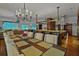 Dining area with an adjacent open floor plan, bar seating, and integrated beach screens; enhanced by a chandelier at 3087 Cherry Ln, Clearwater, FL 33759