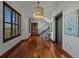 Hallway with wood floors, elegant light fixture, and an elevator; featuring a staircase, wall art, and shuttered windows at 3087 Cherry Ln, Clearwater, FL 33759