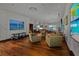 Spacious living area with comfortable seating, a projector, multiple televisions, and sleek hardwood flooring at 3087 Cherry Ln, Clearwater, FL 33759