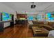 Open living room with a projector, multiple televisions, and seamless hardwood floors throughout at 3087 Cherry Ln, Clearwater, FL 33759