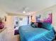 Bright bedroom featuring blue comforter, ceiling fan, and ensuite bathroom at 3188 Lake Pine S Way # B1, Tarpon Springs, FL 34688