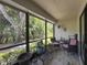 Enclosed porch featuring tile flooring, outdoor seating, and a view of the surrounding greenery at 3188 Lake Pine S Way # B1, Tarpon Springs, FL 34688