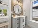 Well-lit bathroom featuring a modern vanity, round mirror, and accent lighting at 3505 N Dartmouth Ave, Tampa, FL 33603