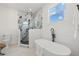 Bright bathroom featuring an oval tub, a glass-enclosed shower with marble-look tile, and modern fixtures at 3505 N Dartmouth Ave, Tampa, FL 33603