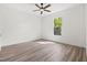 Sun-drenched bedroom featuring wood-look floors, a ceiling fan, and a window with treetop views at 3505 N Dartmouth Ave, Tampa, FL 33603