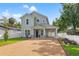 Charming two-story home featuring light green siding, gravel driveway, and a convenient covered parking area at 3505 N Dartmouth Ave, Tampa, FL 33603