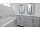 Elegant bathroom featuring double sinks, a marble accent wall, and a soaking tub for ultimate relaxation at 3726 Rain Tree Ct, Palm Harbor, FL 34685