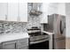 Modern kitchen with mosaic backsplash, stainless steel appliances and white upper cabinets at 3726 Rain Tree Ct, Palm Harbor, FL 34685