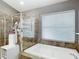Well-lit bathroom with a large soaking tub, tiled shower, and a window with natural light at 5526 Braddock Dr, Zephyrhills, FL 33541