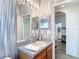 Well-lit bathroom with a single vanity, large mirror, and adjacent laundry room at 5526 Braddock Dr, Zephyrhills, FL 33541