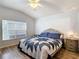 Bright bedroom featuring wood flooring, a ceiling fan, and a large window with a blue and white comforter at 5526 Braddock Dr, Zephyrhills, FL 33541