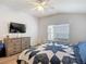 Bright bedroom with ceiling fan, light-colored walls, dresser and television above a blue and white bedspread at 5526 Braddock Dr, Zephyrhills, FL 33541