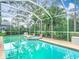 Enclosed pool and jacuzzi with lush backyard landscaping at 5526 Braddock Dr, Zephyrhills, FL 33541