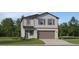 Charming two-story home featuring gray siding, a two-car garage, and manicured landscaping at 5607 Red Kite Dr, Wimauma, FL 33598