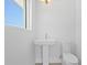 Minimalist powder room featuring pedestal sink and toilet under a bright window at 804 S Davis Blvd, Tampa, FL 33606