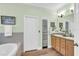 Bathroom view with light green walls, storage cabinet, and tiled bathtub at 8202 Pinewood Run Ct, Tampa, FL 33647