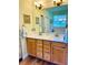 Bathroom vanity with double sinks, light wood cabinets and framed mirror at 8202 Pinewood Run Ct, Tampa, FL 33647