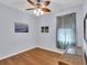 Bedroom with hardwood floors, ceiling fan, and window with sheer curtains at 8202 Pinewood Run Ct, Tampa, FL 33647