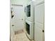A laundry room with stacked washer and dryer, tiled floor, storage cabinets, and a door at 8202 Pinewood Run Ct, Tampa, FL 33647