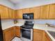 Close-up of kitchen with stainless steel appliances, including oven and microwave, surrounded by wood cabinets and light countertops at 8796 Christie Dr, Largo, FL 33771