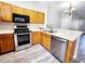 Kitchen area showcasing wood cabinets, stainless steel oven and dishwasher, and a breakfast bar overlooking the dining area at 8796 Christie Dr, Largo, FL 33771
