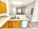 Kitchen view with stainless steel sink and dishwasher, wood cabinets, breakfast bar, and view of an open-concept living area at 8796 Christie Dr, Largo, FL 33771