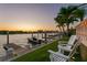 Scenic waterfront view with a boat dock, boat, Adirondack chairs, and palm trees at sunset at 927 Anchorage Rd, Tampa, FL 33602