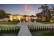 Stunning waterfront home featuring a private dock, outdoor seating, and lush tropical landscaping at twilight at 935 Eden Isle Ne Dr, St Petersburg, FL 33704