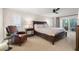 Comfortable main bedroom with ceiling fan, slider to the patio, and a leather reading chair at 935 Eden Isle Ne Dr, St Petersburg, FL 33704