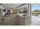 Outdoor kitchen with stainless steel sink and granite countertop overlooking the pool and tropical landscape at 935 Eden Isle Ne Dr, St Petersburg, FL 33704