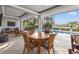 Covered patio with dining table and chairs overlooking the pool, spa, and waterfront view at 935 Eden Isle Ne Dr, St Petersburg, FL 33704