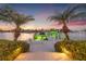 Stunning waterfront property featuring a private dock, boat lift, and picturesque sunset views framed by palm trees at 935 Eden Isle Ne Dr, St Petersburg, FL 33704