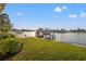 Beautiful waterfront view featuring a private dock with a boat lift and lush green lawn at 935 Eden Isle Ne Dr, St Petersburg, FL 33704