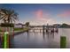 Waterfront view of the home's private dock, Tampa Bay, and tropical landscaping at sunset at 935 Eden Isle Ne Dr, St Petersburg, FL 33704