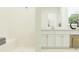 Bright bathroom showcasing a tiled shower, double vanity with white cabinets, and elegant fixtures at 9396 Minnow Ray Dr, Land O Lakes, FL 34638