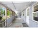 The home's front porch features a wall of windows, a painted floor, and a white entry door at 10130 Burton St, New Port Richey, FL 34654