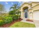Eye-catching home featuring lush landscaping surrounding the blue door and two-car garage at 10223 Charleston Corner Rd, Tampa, FL 33635