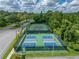 This aerial view shows pickleball and tennis courts amid lush greenery in the Tampa Bay Golf and Country Club Community at 10324 Chatuge Dr, San Antonio, FL 33576