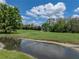 Water view of golf course, featuring pond, green grass, trees and golf cart path at 10324 Chatuge Dr, San Antonio, FL 33576