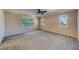 Spacious bedroom featuring three windows, neutral carpet, and ceiling fan at 11386 Churchhill Trl, Seminole, FL 33772