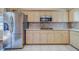 Kitchen featuring stainless steel refrigerator, microwave, and light wood cabinets with plenty of counter space at 11386 Churchhill Trl, Seminole, FL 33772