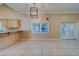 Bright living room featuring a modern light fixture, neutral walls, tile flooring, and access to outdoor space at 11386 Churchhill Trl, Seminole, FL 33772